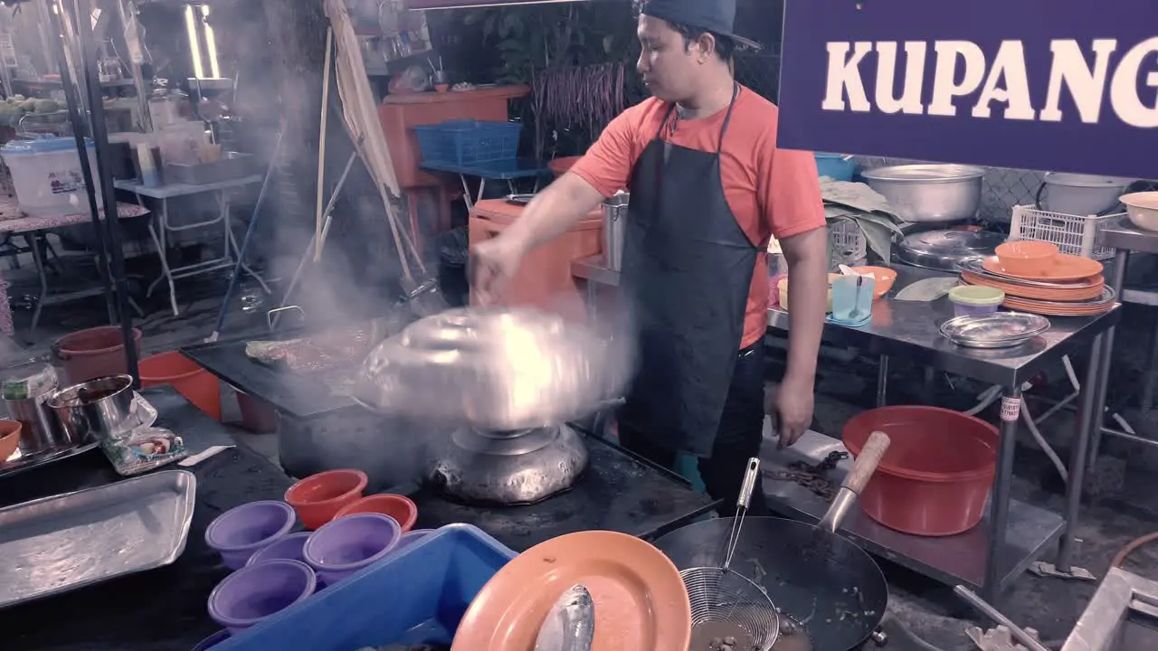 Open-air food stall in Johor with man cooking meat