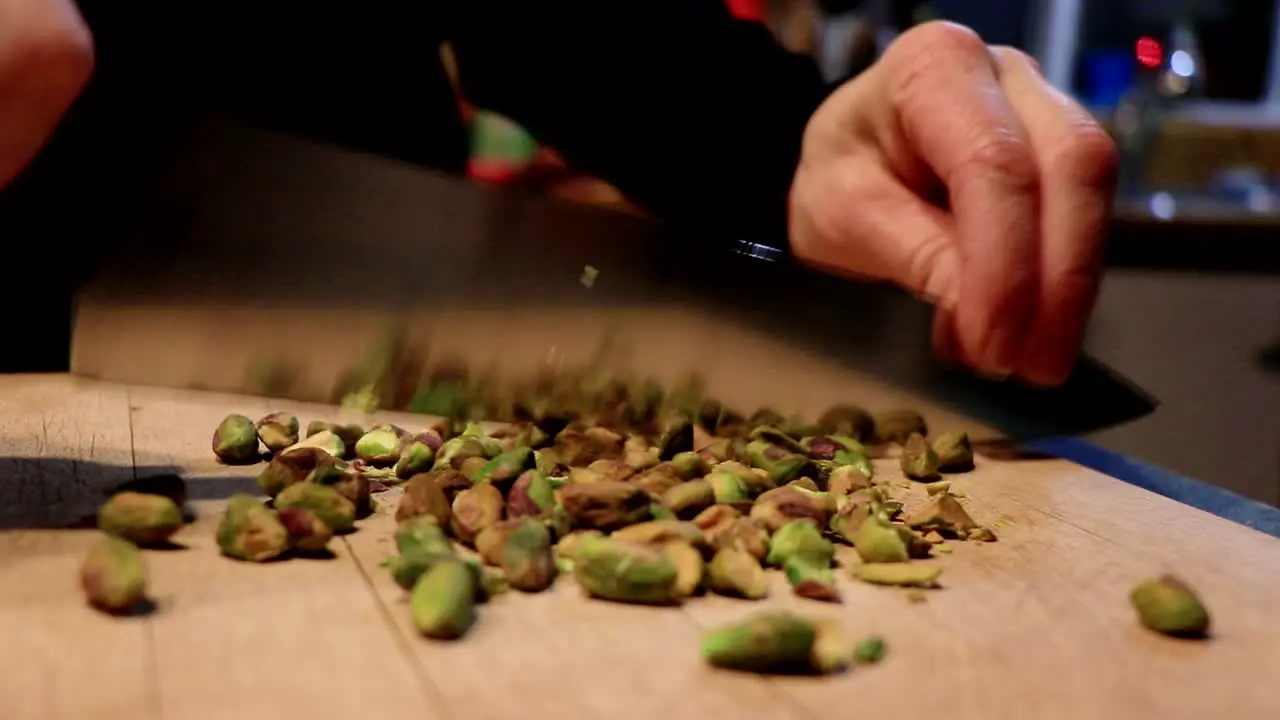 A person cuts some peanuts with a large knife