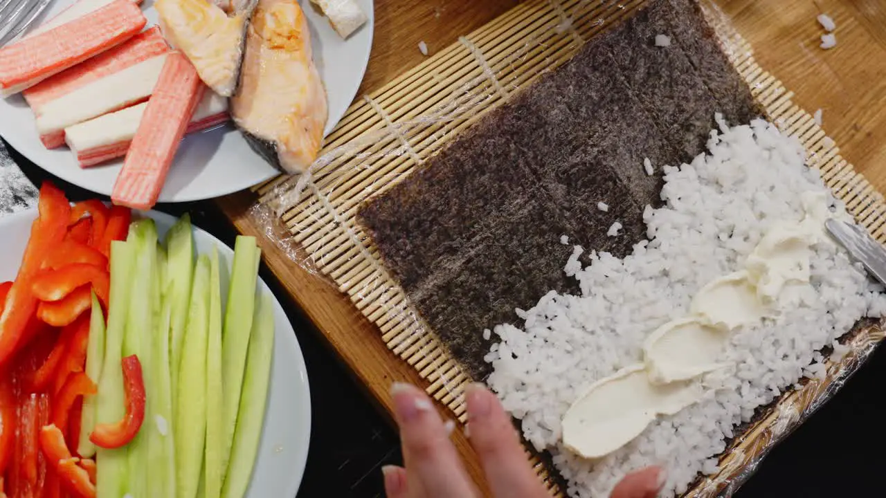 Person Spreading Cream Over Rice All Over With Knife Preparing Sushi Roll Homemade