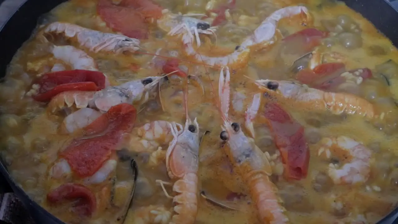 Paella boiling rice and ingredients being cooked on pan