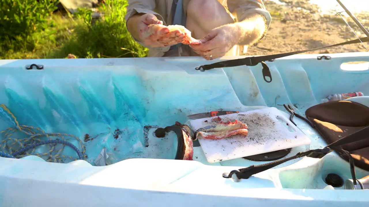 A close up of a man pulling fillets off a flathead fish in Australia on his kayak