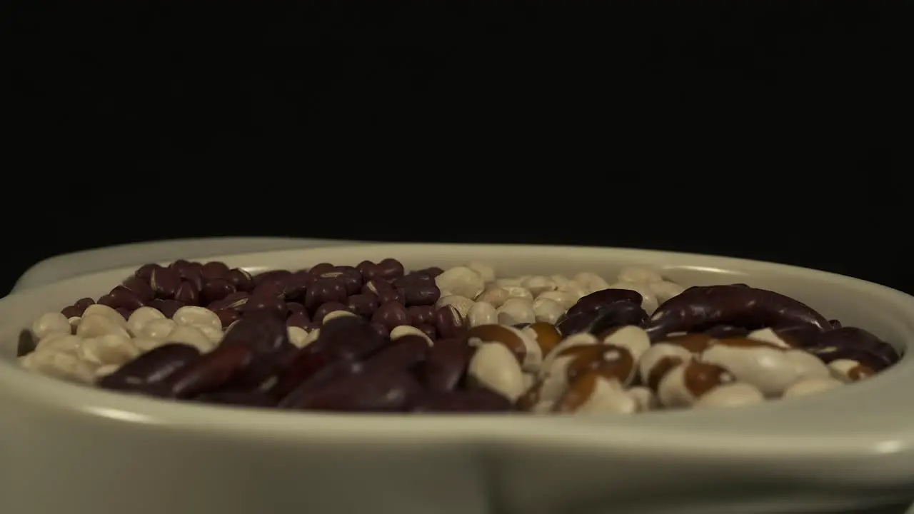 Low angle revolving bowl of dry beans on black background close-up