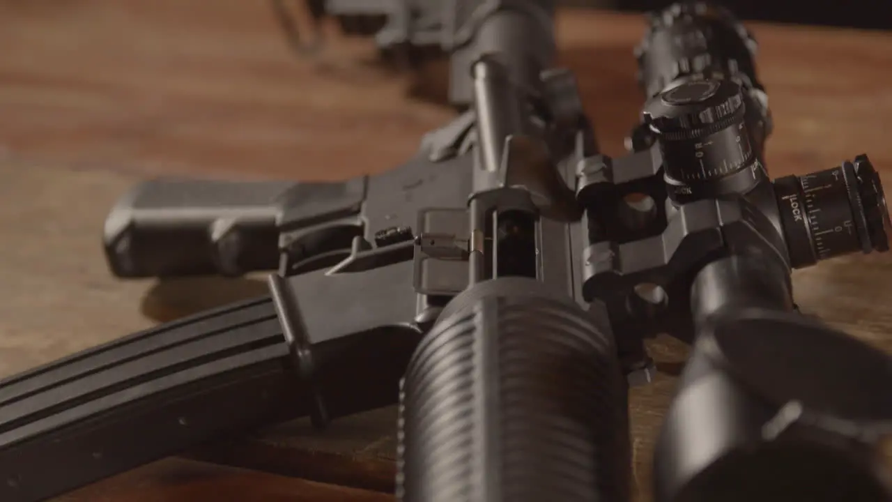 Close dolly over a loaded AR-15 ending on a close up of a barrel aiming towards camera