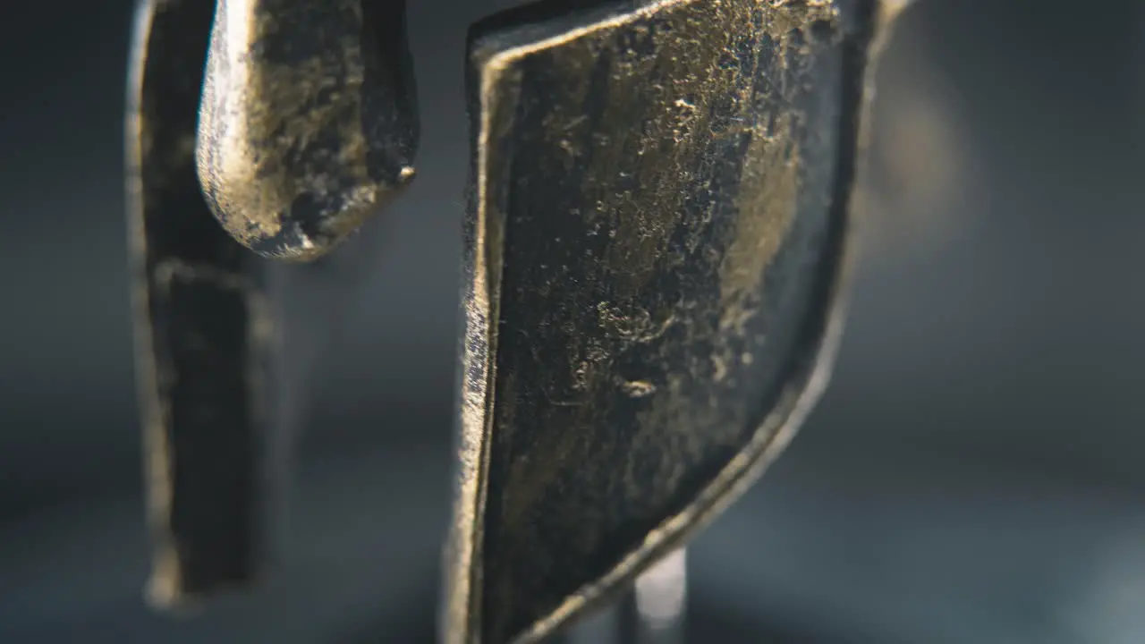 A close up macro detailed slow tilt up shot of a spartan face design warrior metal bronze helmet on a 360 rotating stand studio lighting 4K smooth movement