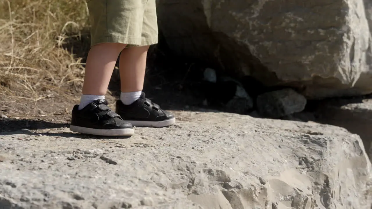 A kid being adventurous walking on top of big rocks