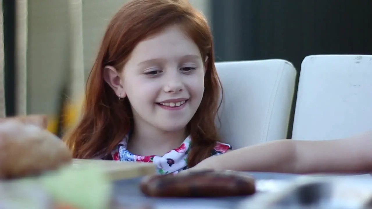 Young smiling girl thanking Dad for her food at backyard picnic with her family