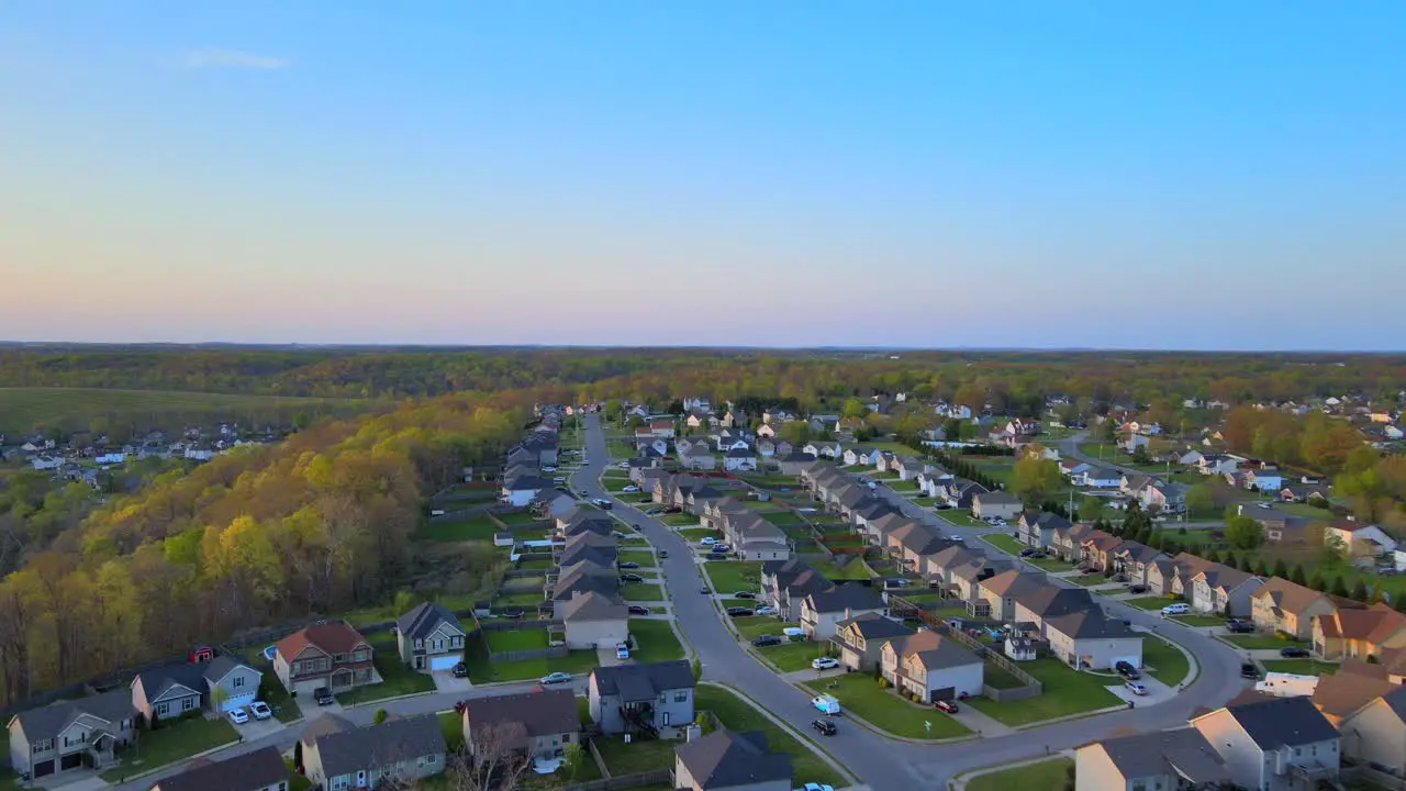 Aerial fly through of beautiful suburban neighborhood with blue skies at sunset