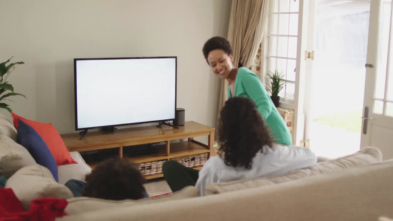 Mixed race lesbian couple and daughter watching tv sitting on couch