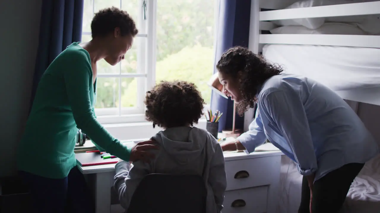 Mixed race lesbian couple helping daughter working at a desk