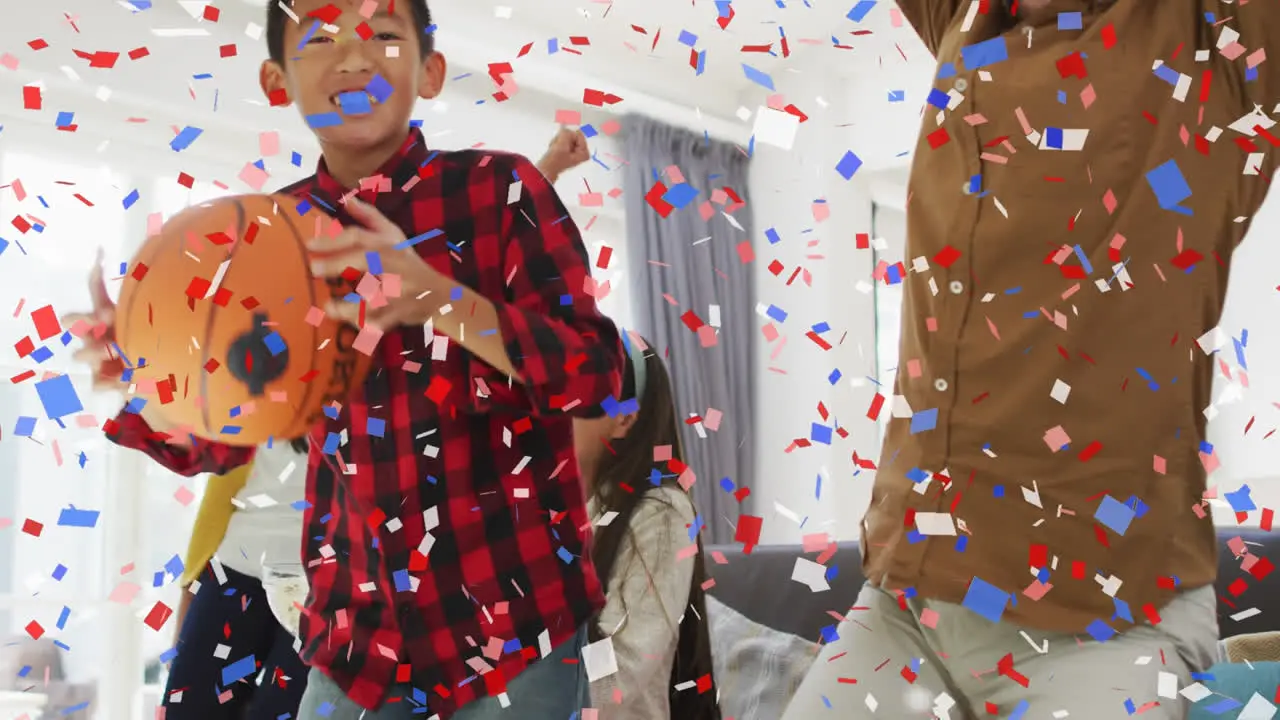 Animation of confetti over parents son and daughter watching sports celebrating at at home