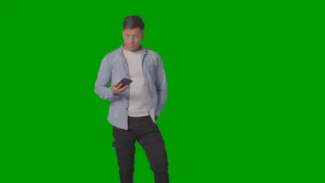 Studio Shot Of Casually Dressed Young Man Ignoring Mobile Phone Call Against Green Screen 1