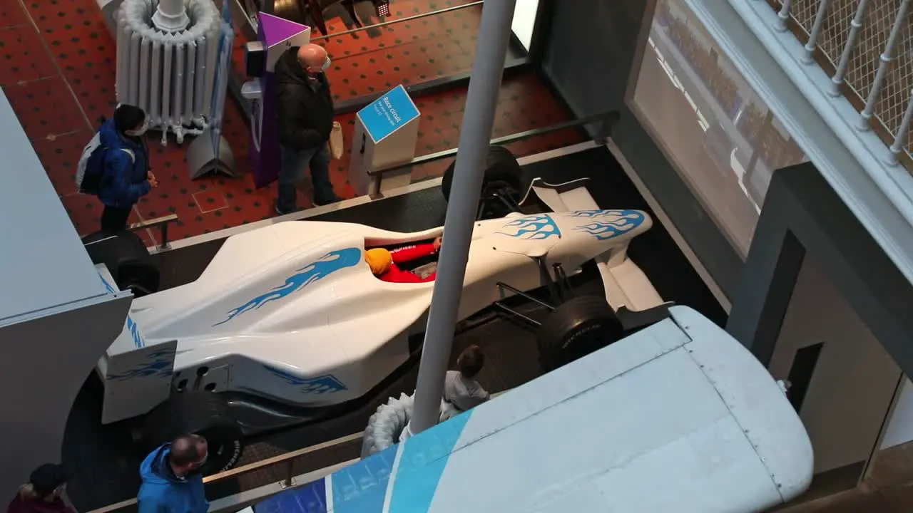 Crowd Watching a Young Boy Having Fun in a Formula One Driving Simulator