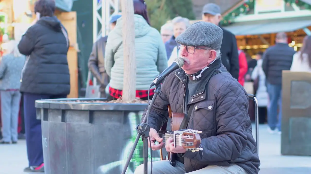 Senior man in cap singing and playing guitar on the street on a frosty day