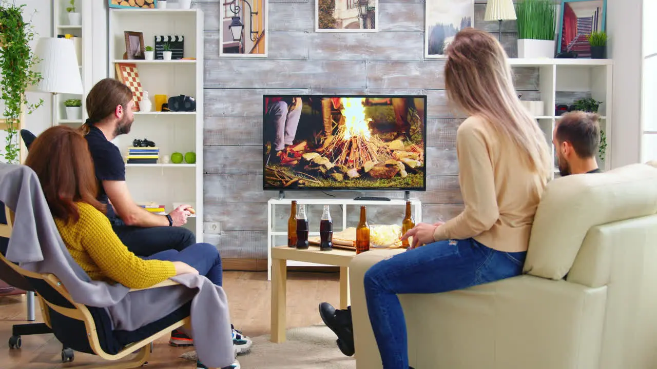 Back view of friends sitting on couch watching a tv show