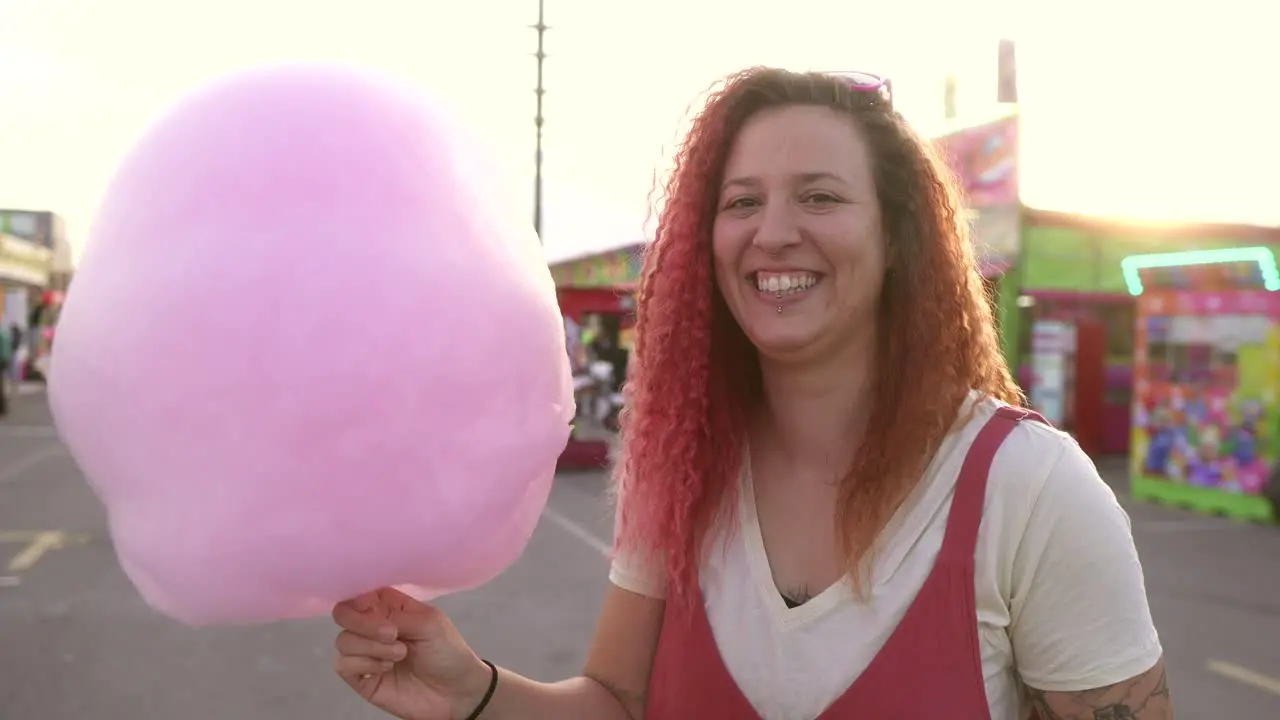 woman smiles and dances excitedly with her cotton candy at the fair