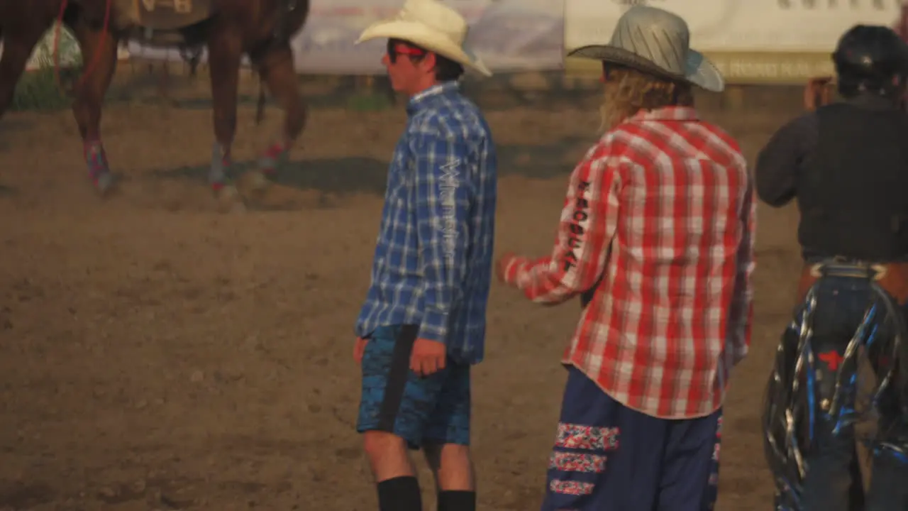 Cowboy walking in the field with horse in the background