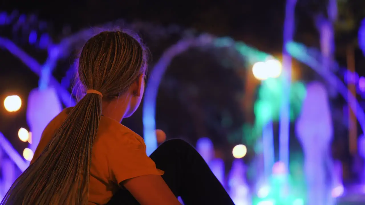 A girl looks at a dancing fountain in a park in the center of Kharkiv