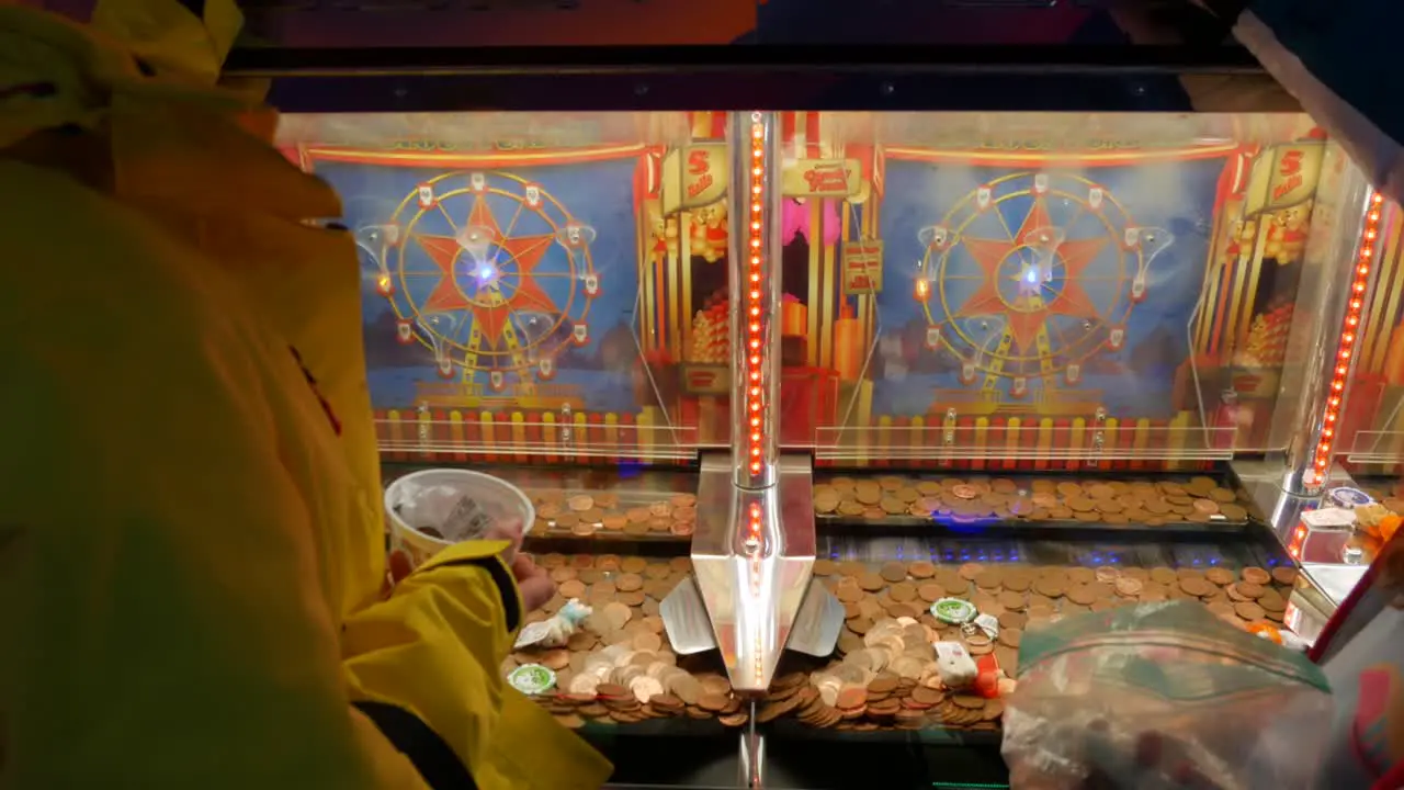 Two Girls Playing on Coin Penny Pusher Solt Machine In An Arcade Casino