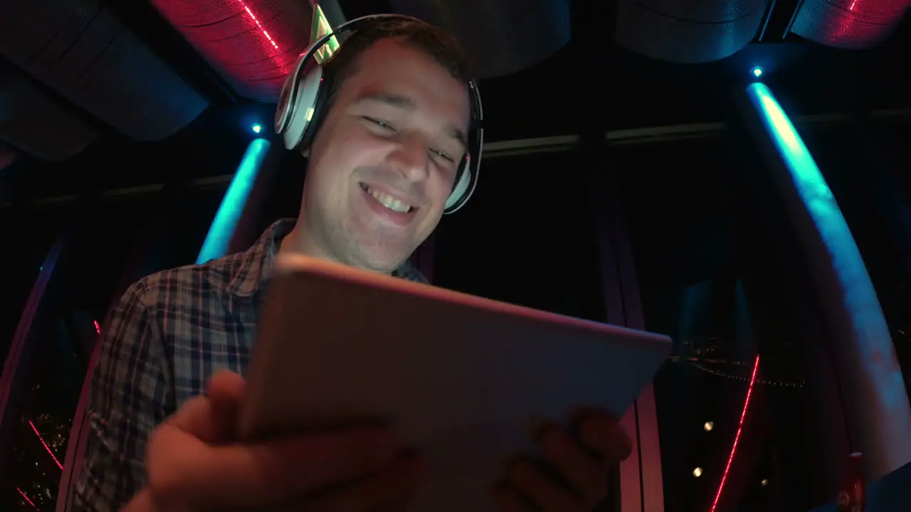 Man enjoying music with pad at sky deck at night