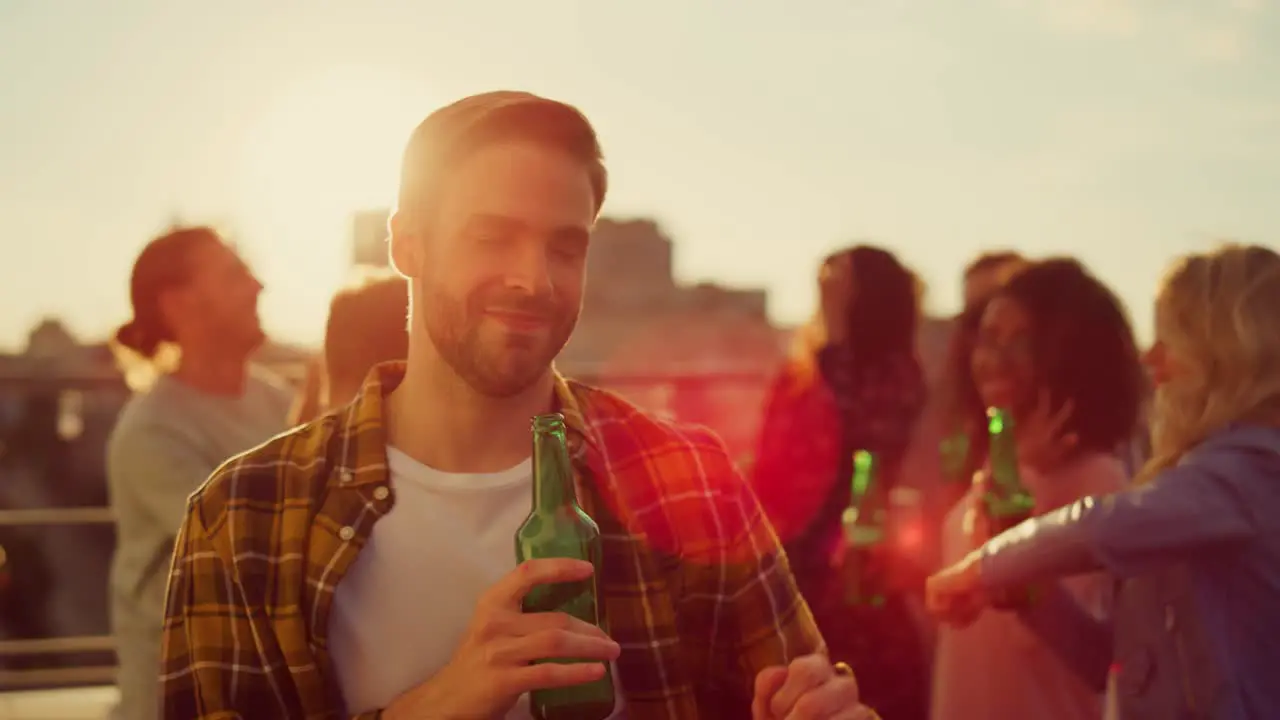 Joyful guy having fun with bottle of beer on rooftop