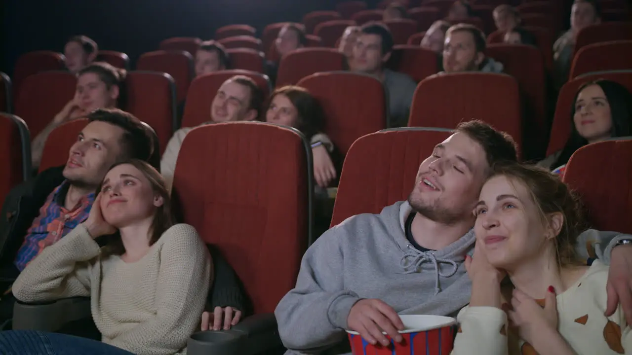 Young people eating popcorn and watching movie