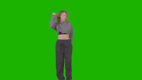 Full Length Studio Shot Of Young Woman Having Fun Dancing Against Green Screen