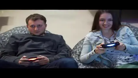 Young couple playing video game at home Shooting and controlling using the game controller