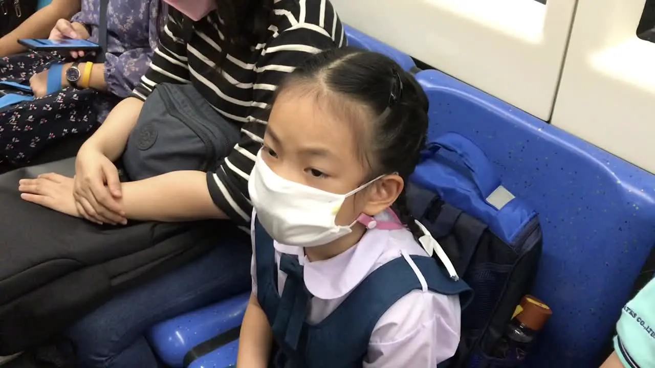 Asian student child girl going to school in the morning wearing a medical mask taking subway or MRT of Thailand