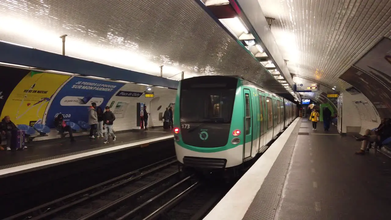 A Paris Metro Train Transportation Leaves Inside Place de Clichy Station France with People Walking By