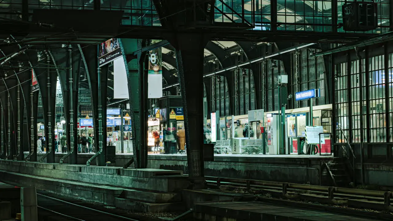 Inside Berlin Friedrichstrasse subway station with commuters and trains speeding nightlife illuminated time lapse