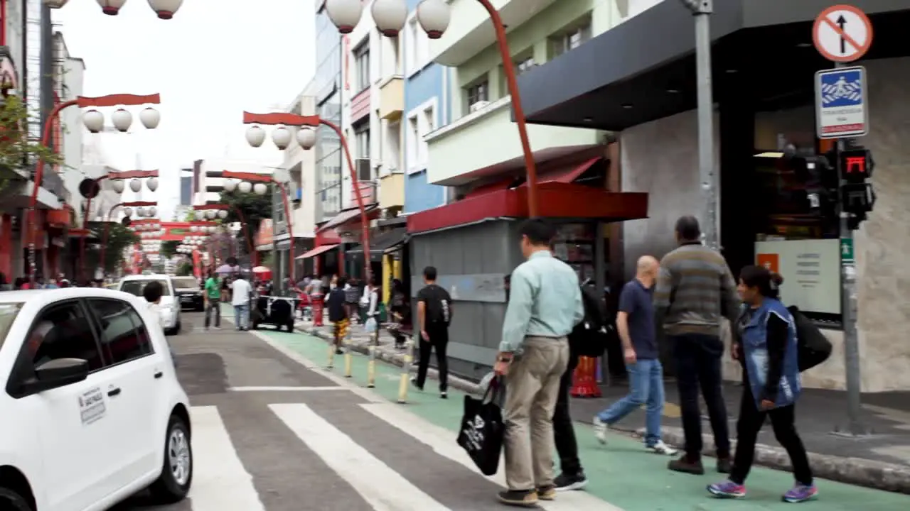 Scene panning from the streetcorner to a view of the entrance of the Japanese neighbourhood of Liberdade in São Paulo Brazil with typical decoration on the main commercial street