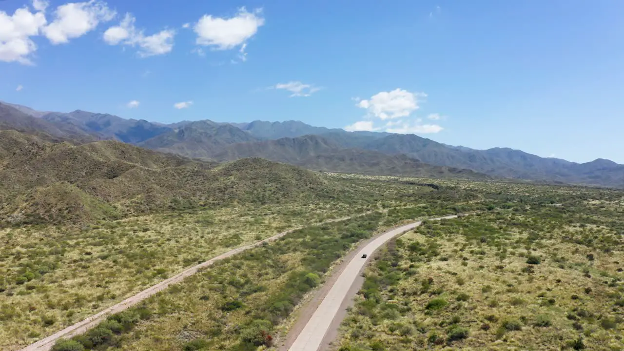 Single vehicle traveling along lonely road in desert valley with blue sky