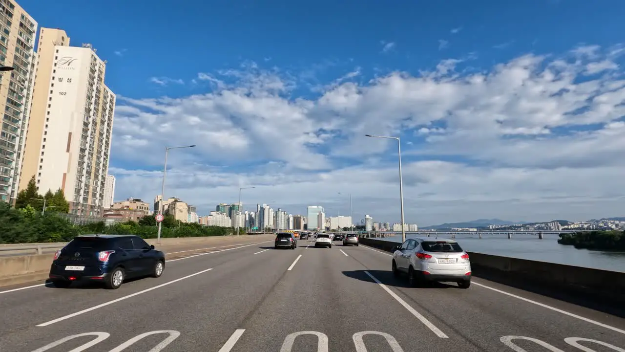 Seoul skyline on summer day driver's perspective driving on Gangbyeonbuk-ro freeway on summer day with white clouds by Han river