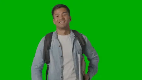 Portrait Of Smiling Male University Or College Student With Laptop Against Green Screen 