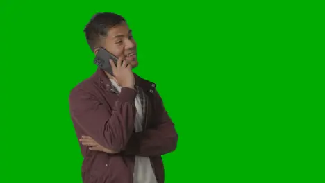 Studio Shot Of Casually Dressed Smiling Young Man Taking Call On Mobile Phone Against Green Screen 2