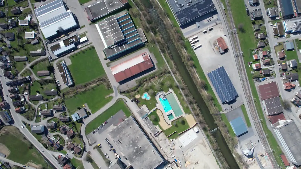 Top down aerial view over a swiss city with a river and an outdoor pool