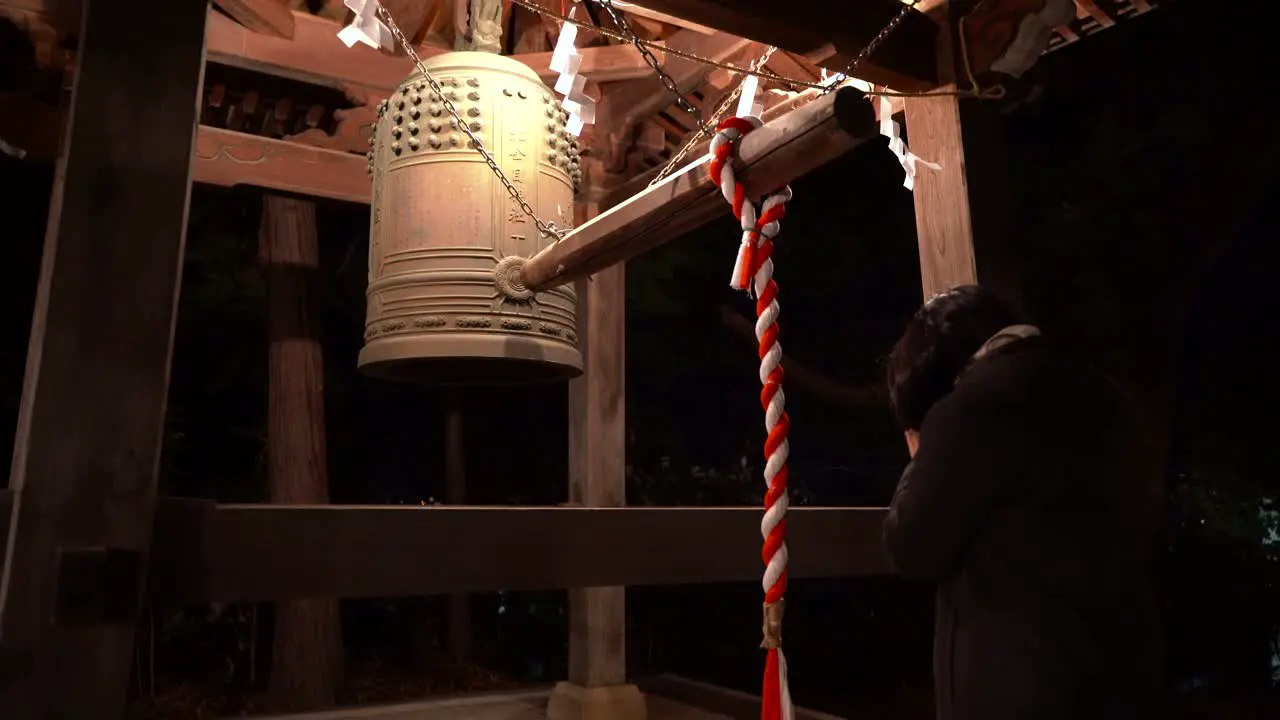 Girl hitting bell in shrine new year tradition Japan