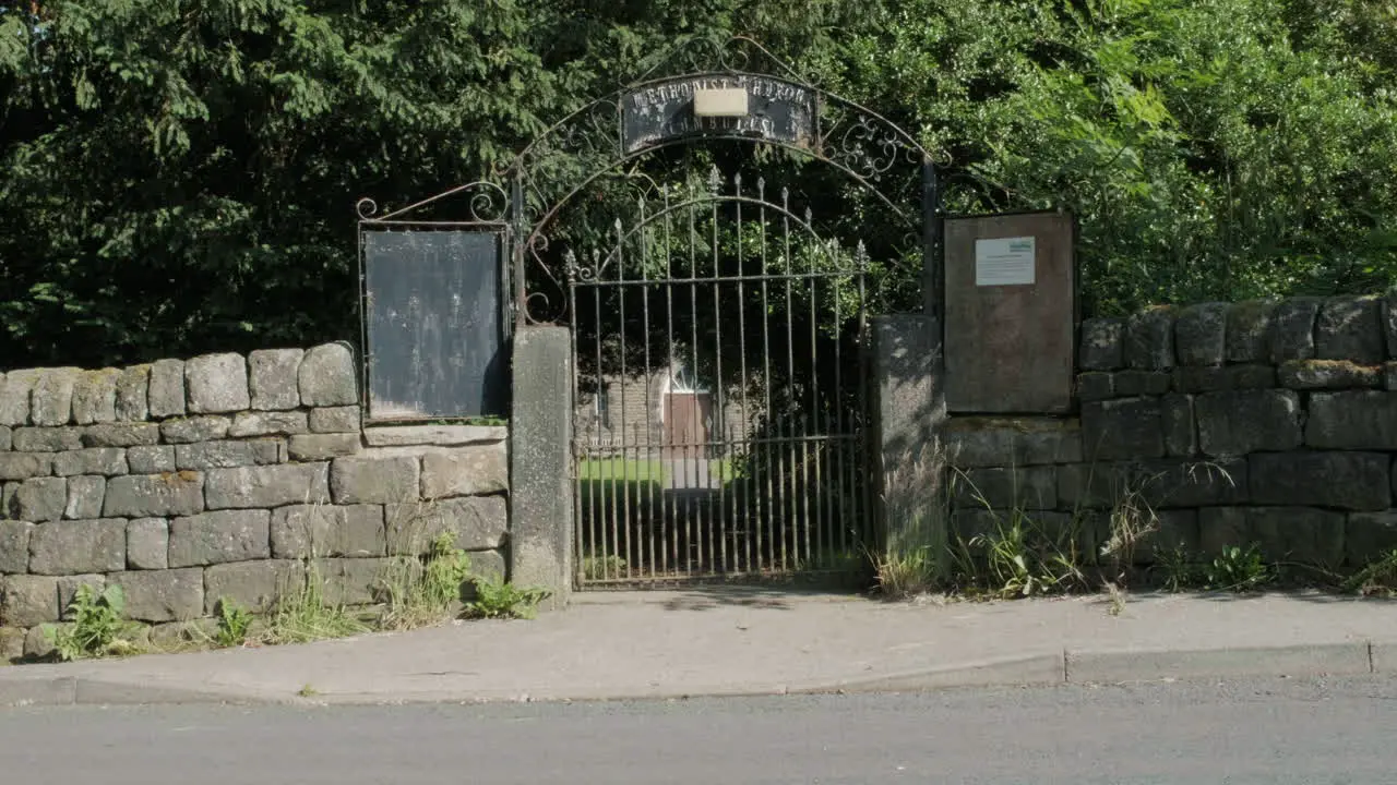 Cemetery gates in high summer gravestones and trees in Yorkshire UK