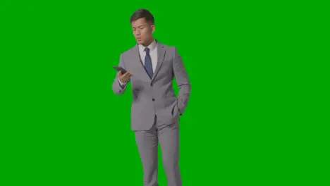 Three Quarter Length Studio Shot Of Unhappy Businessman In Suit Talking On Mobile Phone Against Green Screen 1