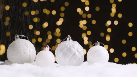 Studio Christmas Still Life With Snow Falling On Decorations With Lights On Background 1