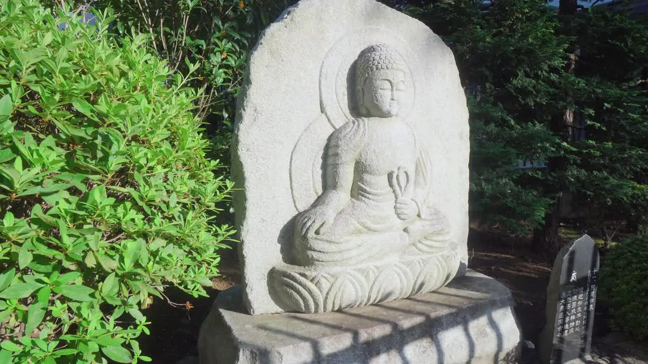 A group of red spider lily next to a Buddha statue in a Tokyo temple