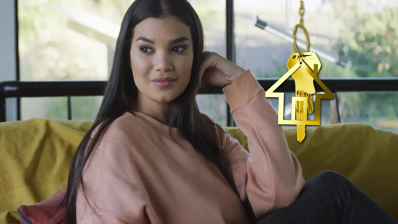 Animation of gold house key and key fob over happy biracial woman at home