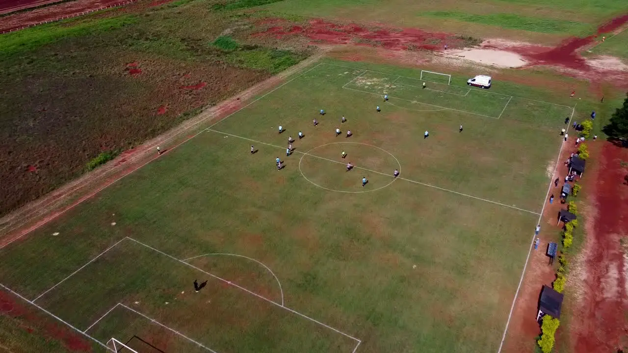 Slow drone approach and pan down on football match closes in on play going for goal