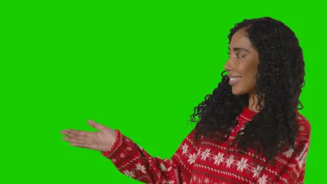 Studio Portrait Of Woman Wearing Christmas Jumper Showing Item Or Object Against Green Screen Smiling At Camera 1