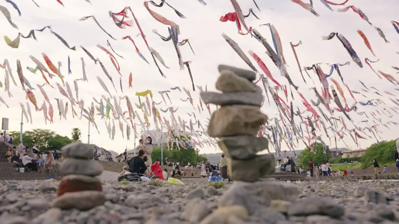 Rack focus reveal from pile of rocks to Japanese families and Carp Flags on children's day