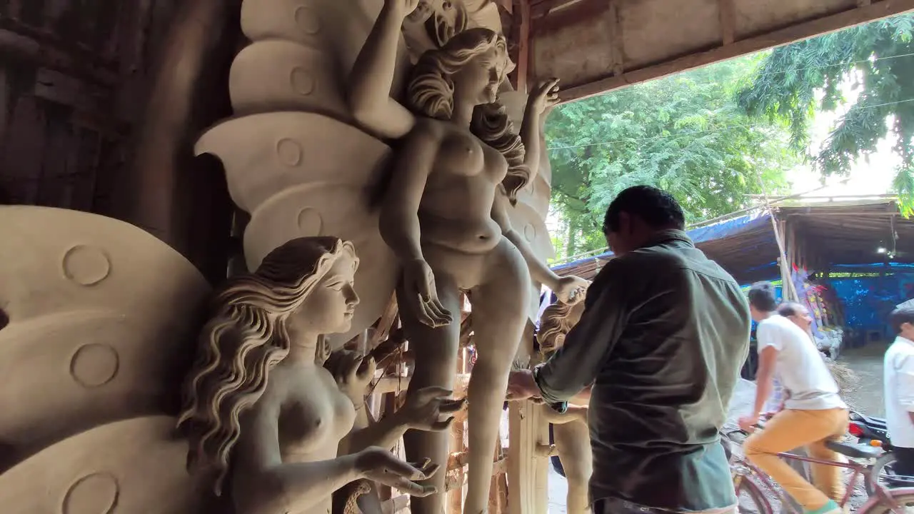 Poor Indian craftsman making clay idol of Gods and Goddess at workshop garage slow camera movement