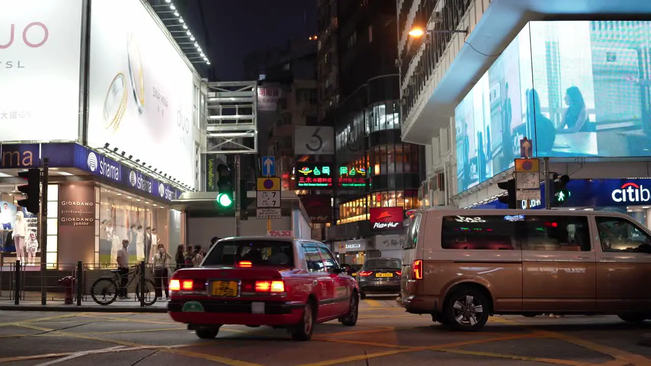 People and cars on a busy street illuminated by advertising billboards