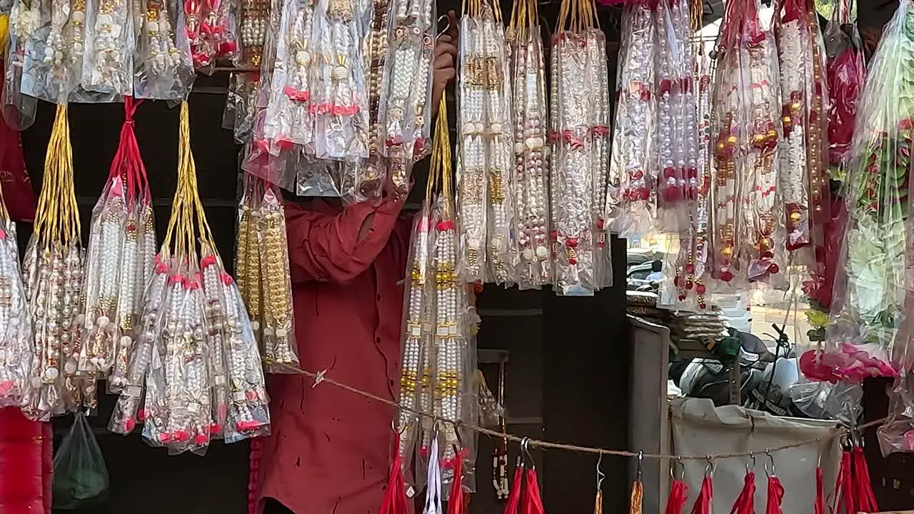 A shopkeeper is arranging garlands for offering to God in his shop