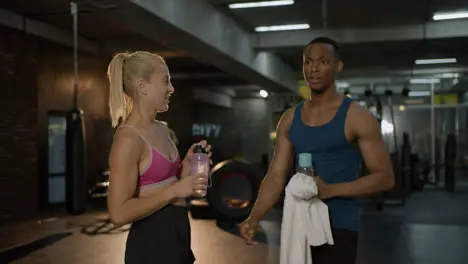 Side view of caucasian female monitor and an athletic african american man in the gym