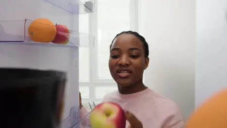 Woman taking apple from the fridge